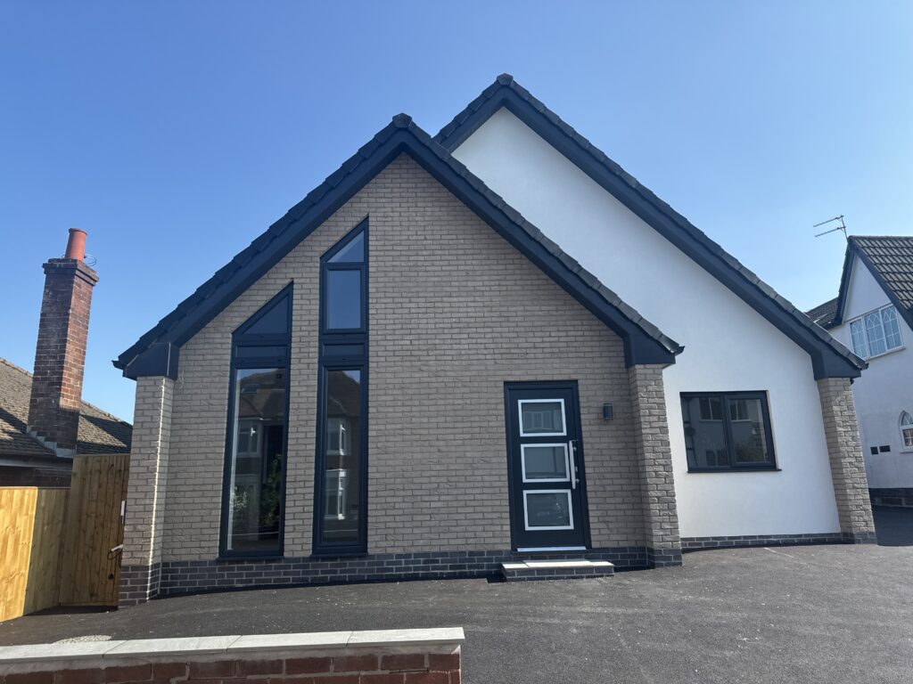 New brick and render house with dark grey front door, tall gable windows and dark frames